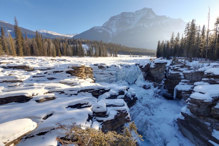 Frozen athabasca falls in the winter with a sun flair