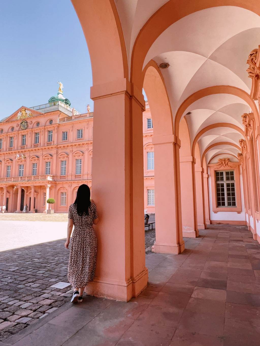 Een vrouw staat in de arcades van het barokke kasteel van Rastatt