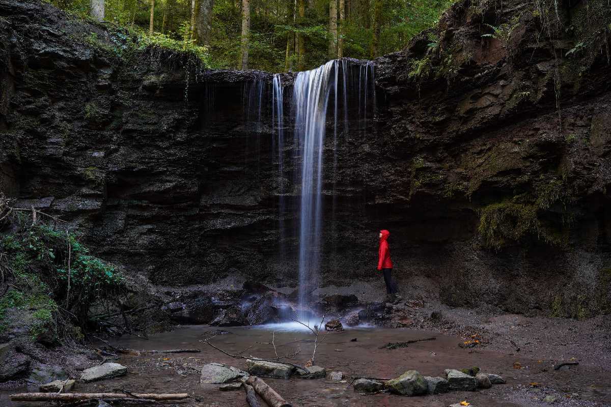 Excursiebestemmingen Stuttgart: een vrouw staat onder de Hörschbach-waterval in het bos